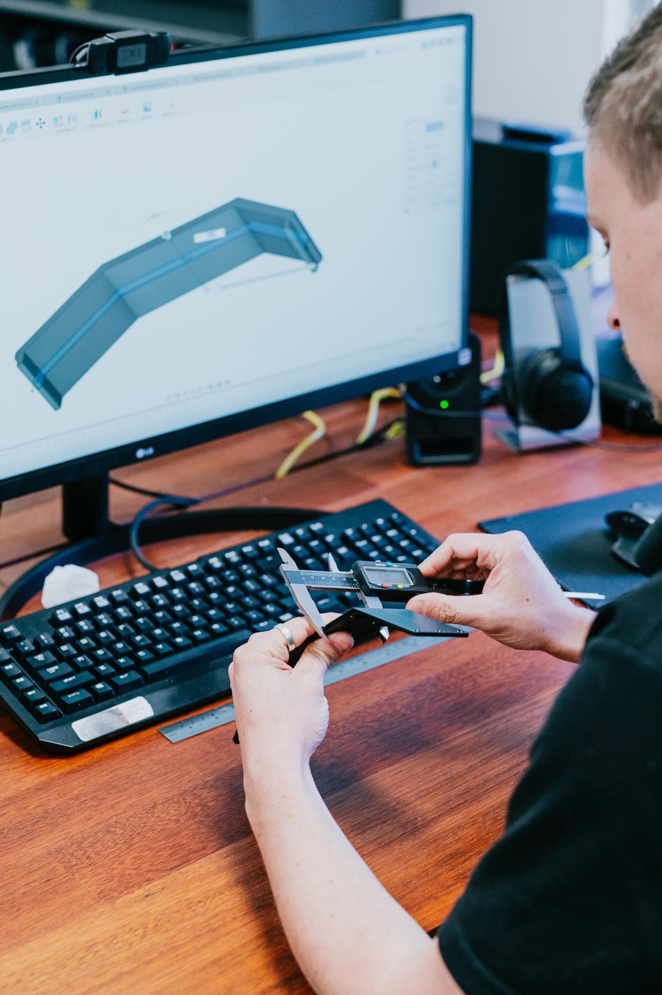 A mechanical engineer checking a machined part against its CAD model